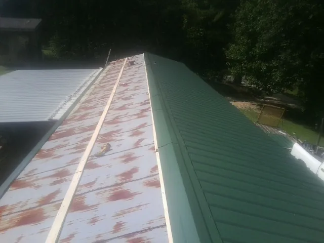 Old rusted panels beside newly installed green metal roofing — Wind Damage Roof Repair by Roofing Brothers in New Paris